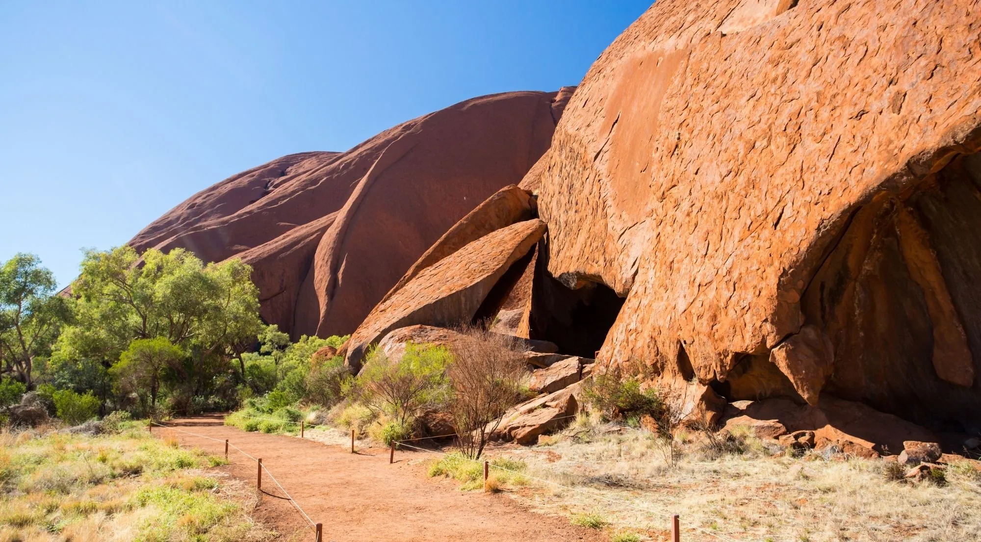 Walking track beside overhangs and caves at the base of Uluru