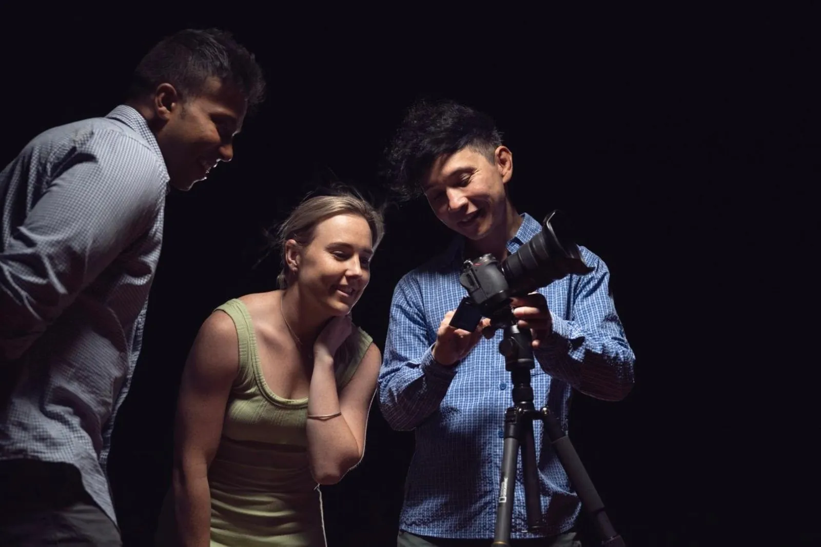 Guide showing two guests their night photo on a camera screen mounted on a tripod